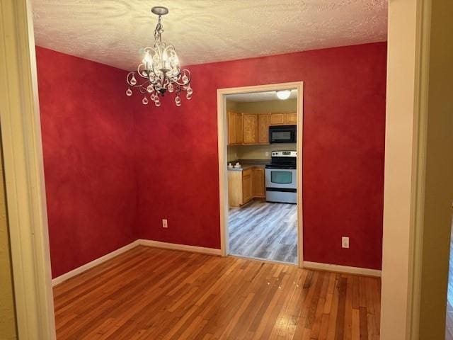 10826 Buffum St, Houston, TX 77051 - unfurnished dining area with light wood-style floors, a chandelier, baseboards, and a textured ceiling