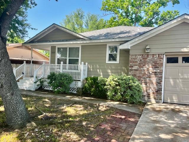 10826 Buffum St, Houston, TX 77051 - view of front of home with brick siding, an attached garage, a porch, and a shingled roof