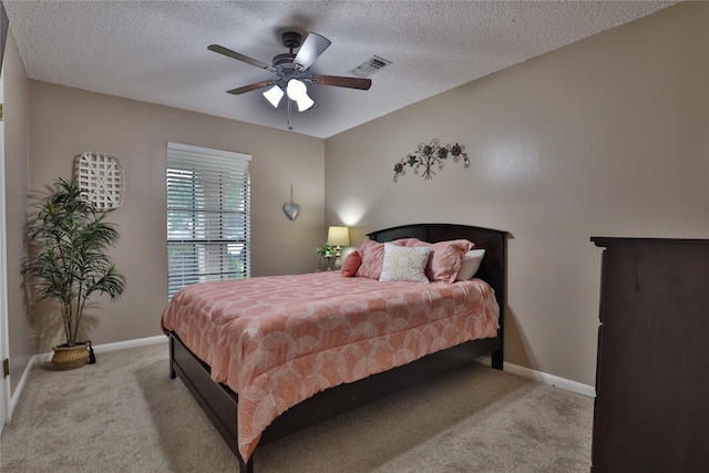 bedroom featuring light carpet, a textured ceiling, baseboards, and ceiling fan