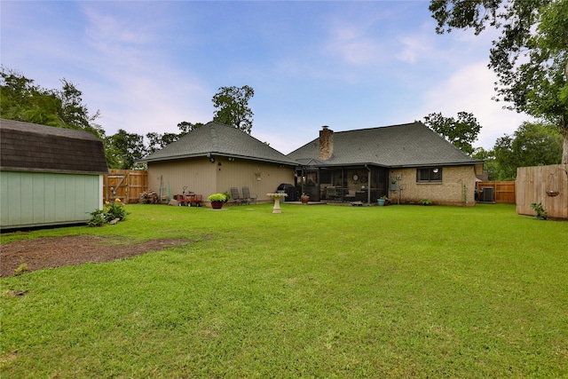 rear view of house with a storage unit, a sunroom, and an outdoor structure