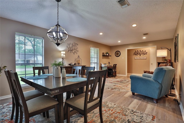 dining space featuring light wood-style flooring, healthy amount of natural light, a chandelier, a textured ceiling, and recessed lighting
