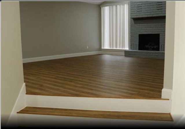 1703 Grand Valley Dr, Houston, TX 77090 - unfurnished living room with wood finished floors, baseboards, and a brick fireplace