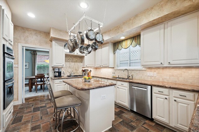 kitchen with appliances with stainless steel finishes, a sink, a center island, white cabinetry, and recessed lighting