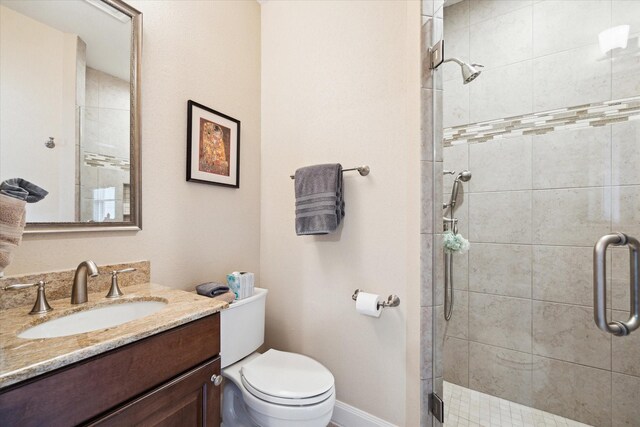 full bath featuring a shower stall, toilet, vanity, and baseboards