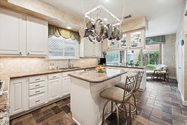 kitchen featuring a sink, plenty of natural light, white cabinetry, and tasteful backsplash