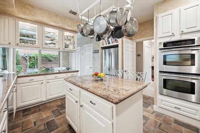 kitchen featuring stainless steel appliances, light stone counters, white cabinetry, and glass insert cabinets