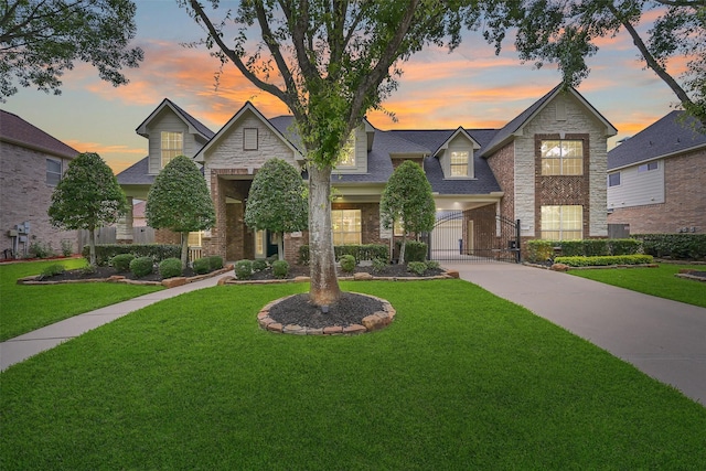 view of front of house with stone siding, a gate, a yard, and concrete driveway