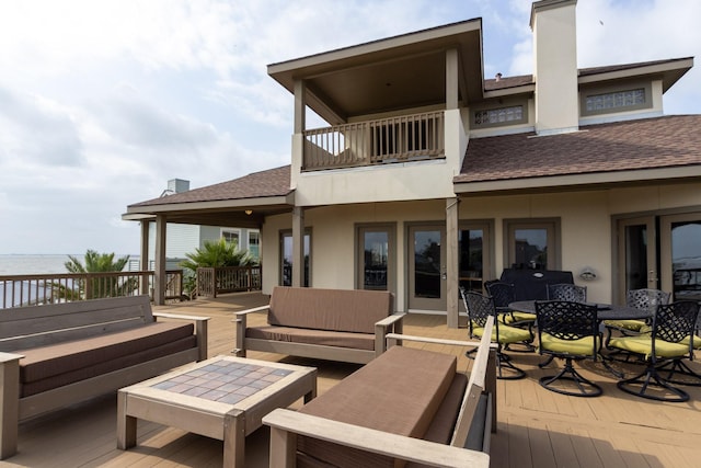 wooden deck with an outdoor living space, outdoor dining area, and a water view