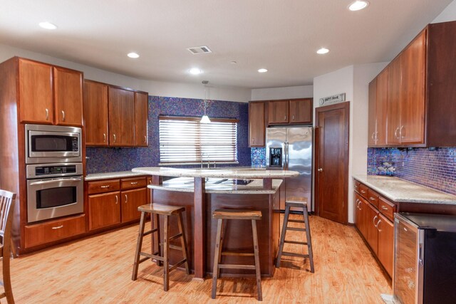 kitchen featuring stainless steel appliances, a kitchen bar, tasteful backsplash, light wood-style flooring, and recessed lighting
