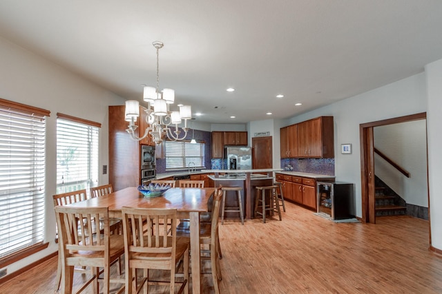 dining space featuring a chandelier, light wood-style floors, beverage cooler, recessed lighting, and stairway