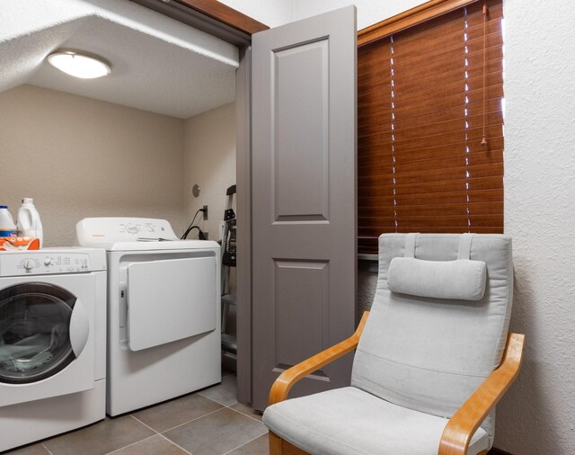 laundry area with washer and clothes dryer, tile patterned floors, and a textured wall