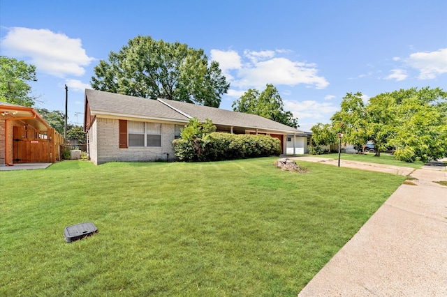 single story home featuring driveway, a garage, a front lawn, and brick siding
