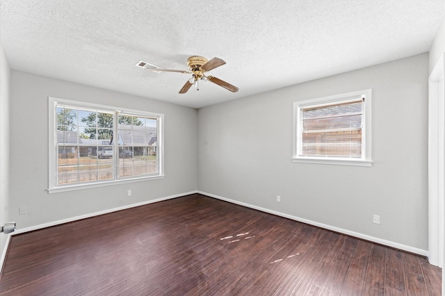 unfurnished room with dark wood-type flooring, a ceiling fan, baseboards, and a textured ceiling