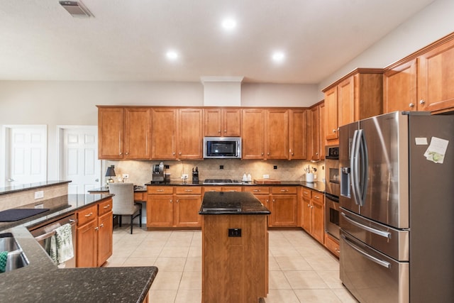 1886 Pampas Trail Dr, Friendswood, TX 77546 - kitchen featuring stainless steel appliances, a center island, decorative backsplash, light tile patterned floors, and brown cabinetry