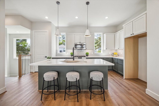 526 Janisch Rd, Houston, TX 77018 - kitchen featuring stainless steel microwave, decorative backsplash, light wood-type flooring, light countertops, and recessed lighting