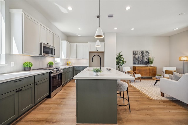 526 Janisch Rd, Houston, TX 77018 - kitchen with appliances with stainless steel finishes, a sink, gray cabinets, tasteful backsplash, and an island with sink