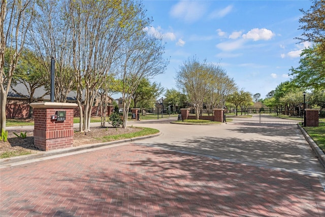 view of decorative street featuring a gate, curbs, and a gated entry