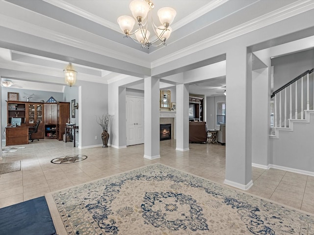 tiled entryway featuring ceiling fan, a lit fireplace, a chandelier, baseboards, and stairway