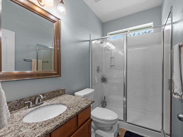 bathroom with a stall shower, toilet, and vanity