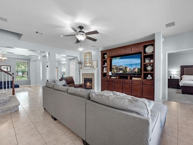 living room with light tile patterned floors, a glass covered fireplace, a ceiling fan, and baseboards