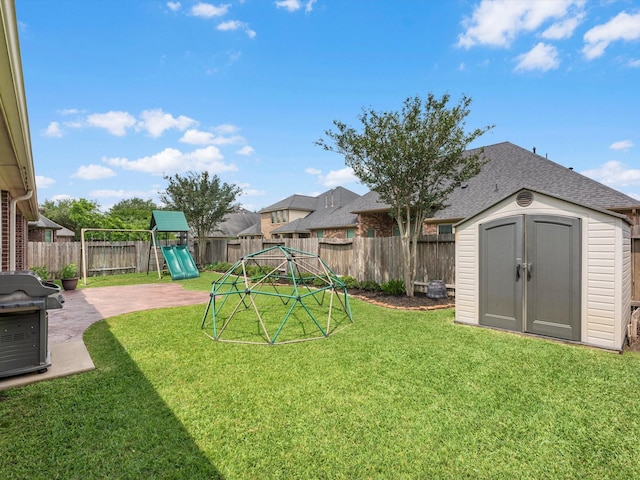 view of yard with a playground, a storage unit, an outbuilding, and a patio area