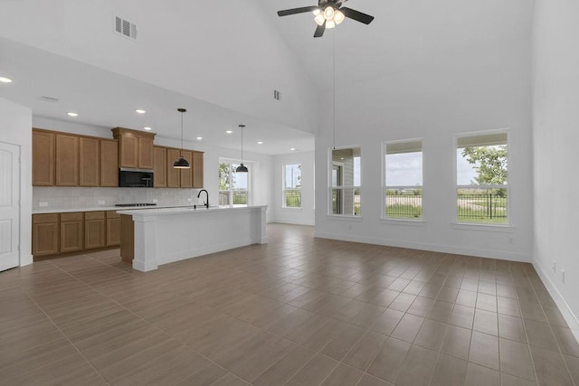 8235 Red Shiner Way, Fulshear, TX 77441 - kitchen with stainless steel microwave, brown cabinetry, tasteful backsplash, light countertops, and open floor plan