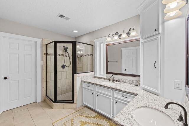 full bath featuring a stall shower, vanity, tile patterned floors, and a textured ceiling
