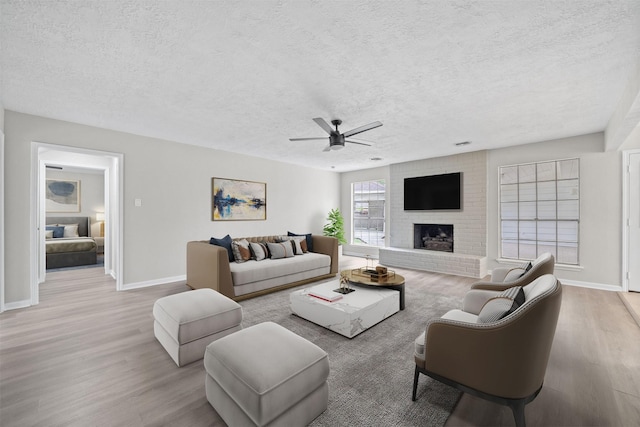 3915 Glenheather Dr, Houston, TX 77068 - living room with wood finished floors, a textured ceiling, ceiling fan, baseboards, and a fireplace