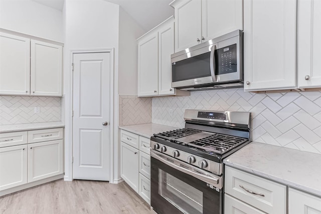 kitchen with stainless steel appliances, tasteful backsplash, white cabinets, and light stone countertops