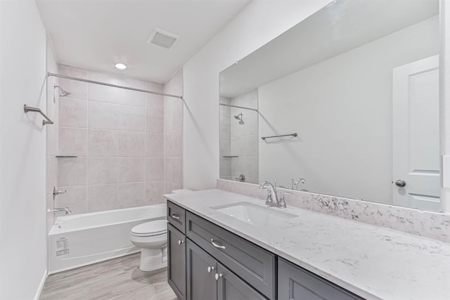 bathroom with toilet, wood finished floors, shower / bath combination, and vanity