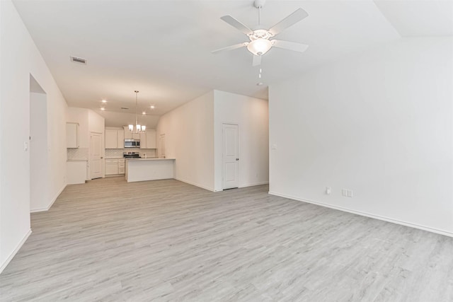 unfurnished living room with light wood-type flooring, ceiling fan, a chandelier, baseboards, and vaulted ceiling
