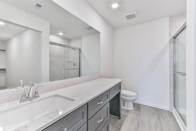 full bath with wood finished floors, a shower stall, toilet, vanity, and baseboards