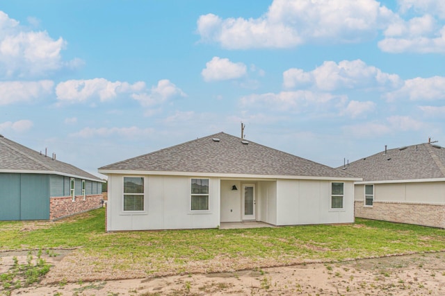 rear view of property featuring roof with shingles, a lawn, and a patio area