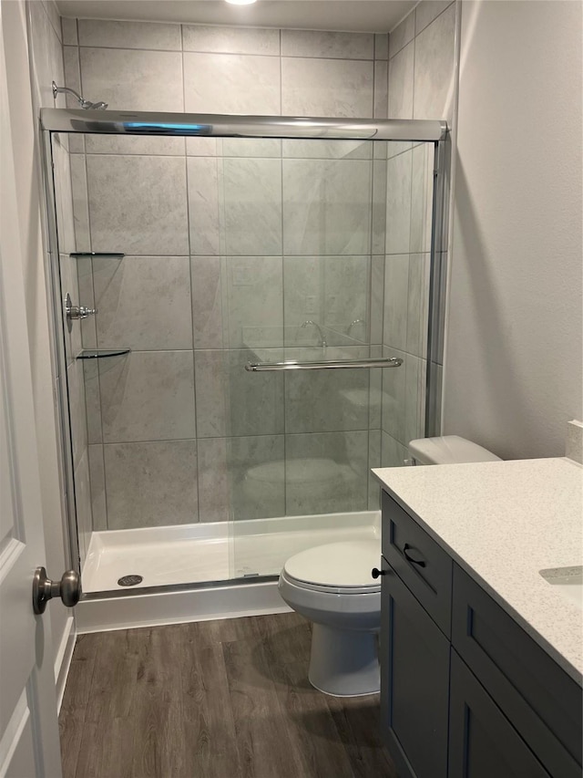 full bathroom with wood finished floors, a shower stall, toilet, and vanity
