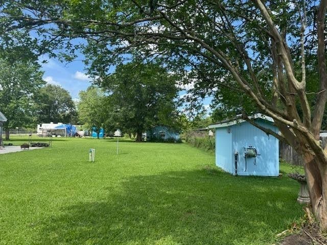 view of green lawn featuring a storage unit and an outbuilding
