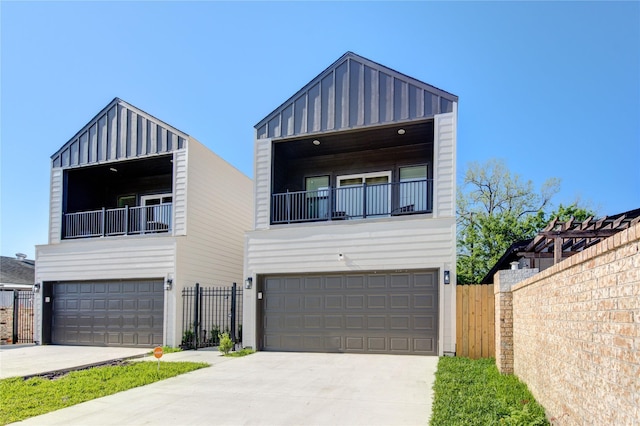 contemporary house with a garage, fence, driveway, and board and batten siding