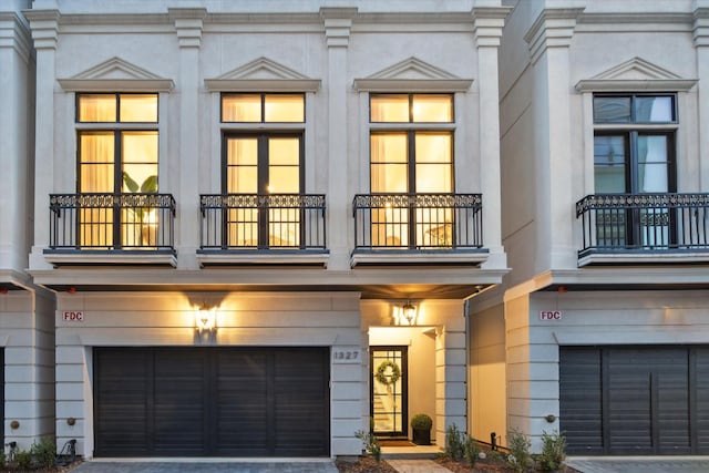 multi unit property with a balcony, a garage, and driveway