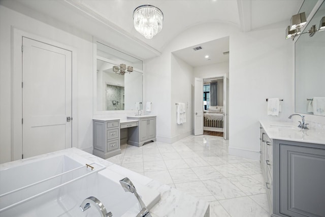 ensuite bathroom with baseboards, a chandelier, marble finish floors, a garden tub, and two vanities