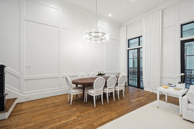 dining room with a decorative wall, a chandelier, wood finished floors, ornamental molding, and recessed lighting