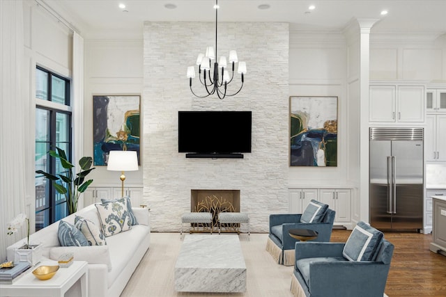 living room featuring wood finished floors, a chandelier, a fireplace, ornamental molding, and recessed lighting