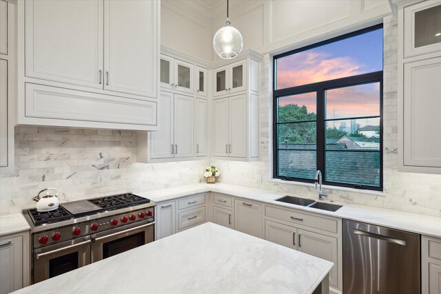 kitchen featuring appliances with stainless steel finishes, a sink, backsplash, light countertops, and ornamental molding