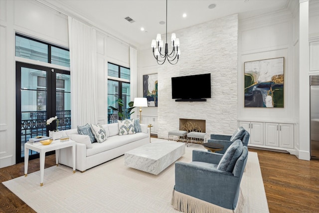 living room featuring a chandelier, wood finished floors, recessed lighting, and a stone fireplace