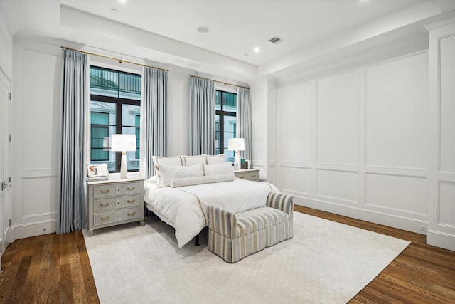 bedroom with a decorative wall, dark wood finished floors, and recessed lighting