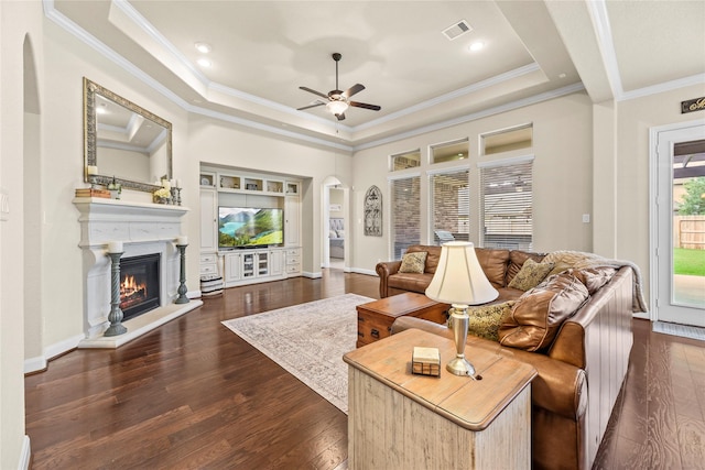 18814 Luby Creek Dr, Cypress, TX 77433 - living area featuring arched walkways, a tray ceiling, ornamental molding, a glass covered fireplace, and a ceiling fan