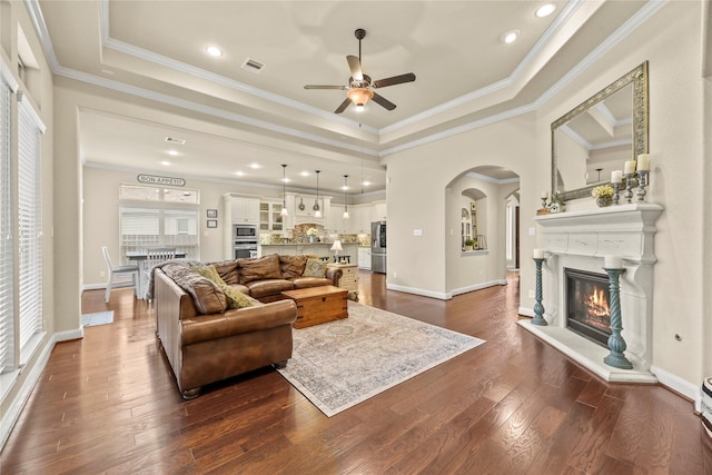 18814 Luby Creek Dr, Cypress, TX 77433 - living area with a ceiling fan, dark wood-type flooring, a glass covered fireplace, a raised ceiling, and baseboards
