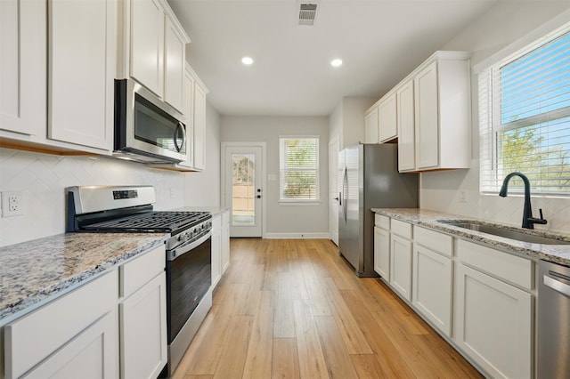 820 Dawn Redwood Ct, Conroe, TX 77304 - kitchen featuring stainless steel appliances, a sink, light wood-style floors, white cabinets, and baseboards