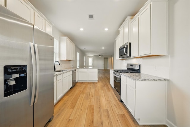 820 Dawn Redwood Ct, Conroe, TX 77304 - kitchen with appliances with stainless steel finishes, a sink, light wood finished floors, a ceiling fan, and recessed lighting