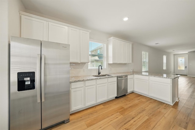 820 Dawn Redwood Ct, Conroe, TX 77304 - kitchen featuring stainless steel appliances, a sink, white cabinetry, light wood-style floors, and a peninsula