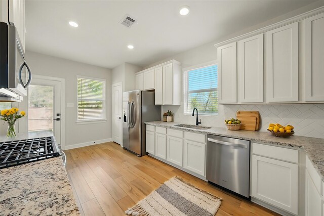 820 Dawn Redwood Ct, Conroe, TX 77304 - kitchen featuring appliances with stainless steel finishes, a sink, healthy amount of natural light, white cabinets, and recessed lighting