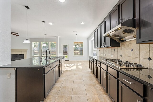 2642 Tacoma Springs Dr, Conroe, TX 77304 - kitchen featuring a sink, stainless steel gas cooktop, tasteful backsplash, under cabinet range hood, and light tile patterned floors